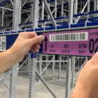 close up of worker applying warehouse magnet label on racking